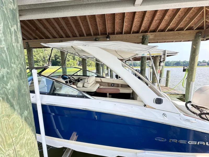 Slide: The Image of 2019 Regal 29 OBX boat docked under a wooden shelter by the water. - 41
