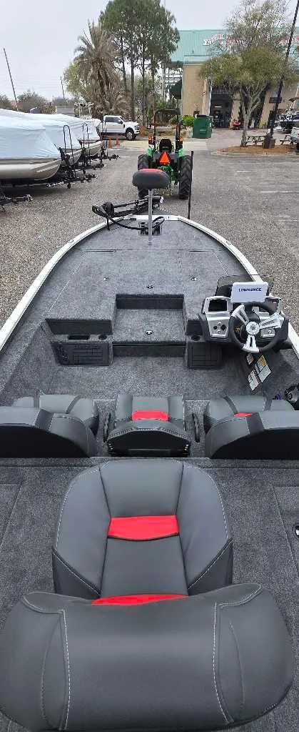 Slide: The Image of 2025 Tracker Savage 215 boat interior with steering console and seating, parked outdoors. - 4