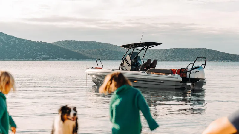 Slide: The Image of 2025 Highfield ADV7 boat anchored in serene waters with people and a dog nearby. - 6