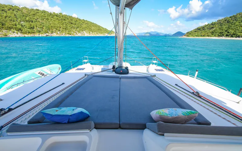Slide: The Image of Lagoon 450F 2015 catamaran with sunbathing area, turquoise sea, and lush green islands. - 12