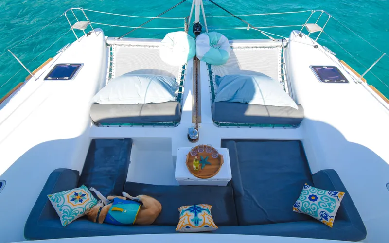 Slide: The Image of Lagoon 450F 2015 catamaran deck with cushions and pillows, overlooking turquoise water. - 13