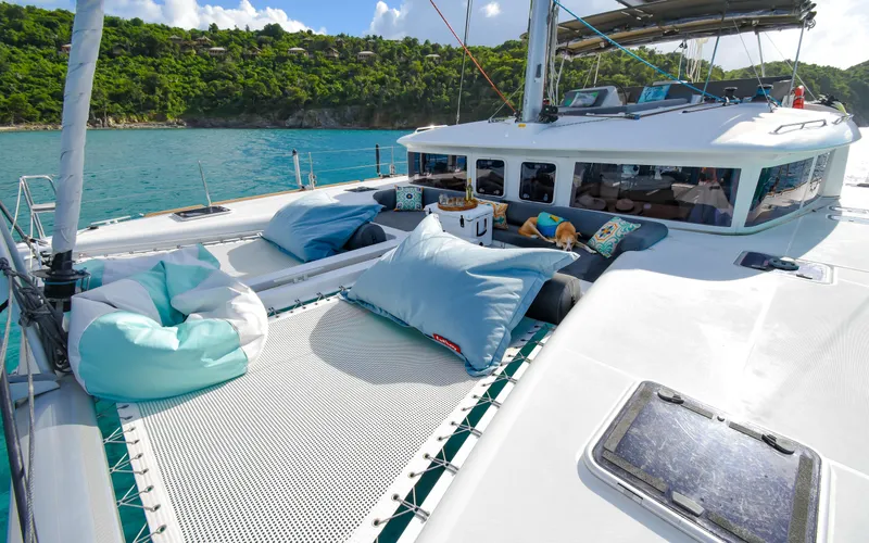 Slide: The Image of 2015 Lagoon 450F catamaran with comfortable deck seating, anchored in a scenic bay. - 9