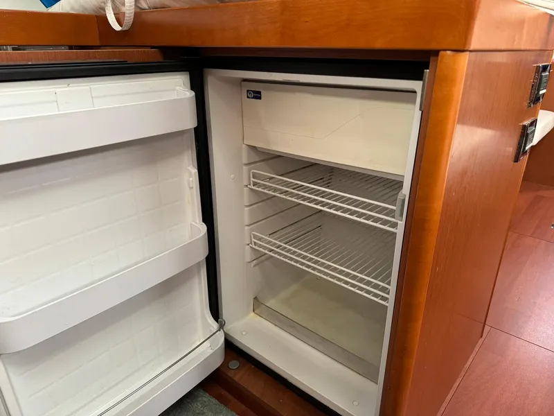 Slide: The Image of Open refrigerator inside 2014 Beneteau Oceanis 48 yacht, featuring wooden cabinetry. - 35