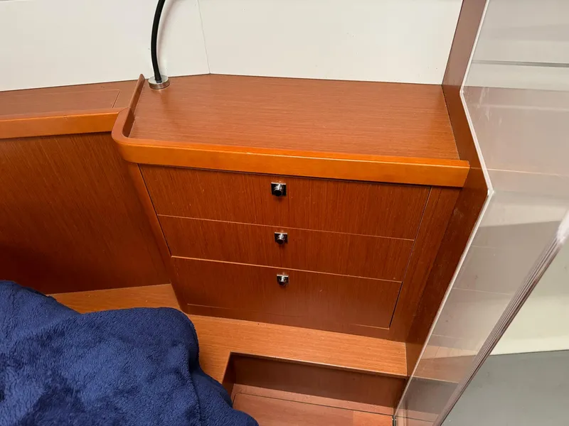 Slide: The Image of Interior of 2014 Beneteau Oceanis 48 yacht with wooden drawers and blue bedding. - 42
