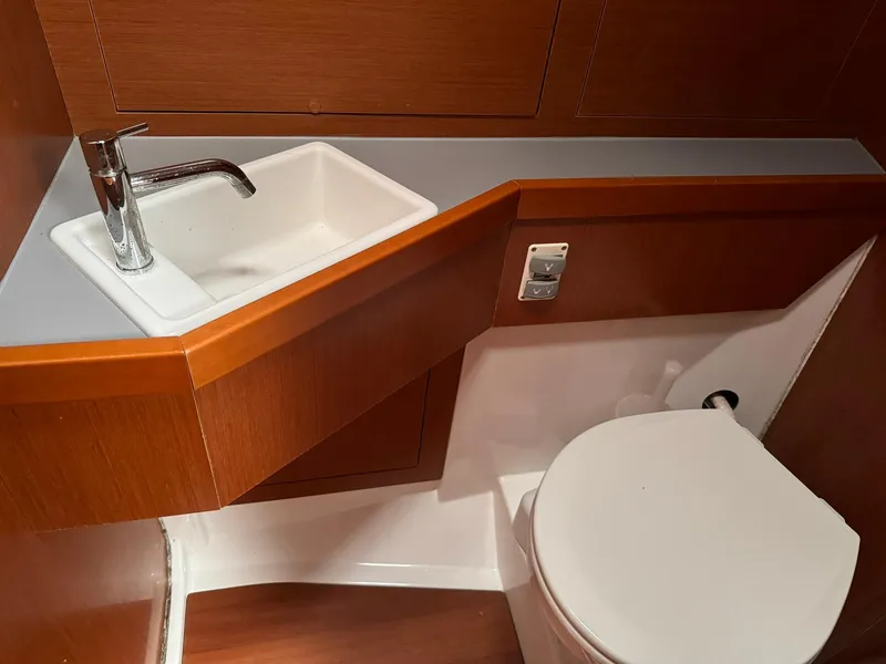 Slide: The Image of 2014 Beneteau Oceanis 48 bathroom with sink and toilet, featuring wooden cabinetry. - 45