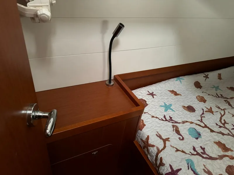 Slide: The Image of Cabin interior of 2014 Beneteau Oceanis 48 with wooden finish and nautical-themed bedding. - 47