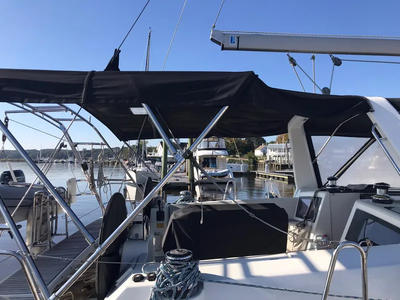 Slide: The Image of 2014 Beneteau Oceanis 48 sailboat docked, featuring a spacious cockpit and black canopy. - 72