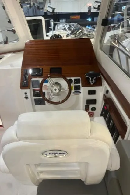 Slide: The Image of 2025 NorthCoast 285 HT boat helm with wooden dashboard and steering wheel. - 22