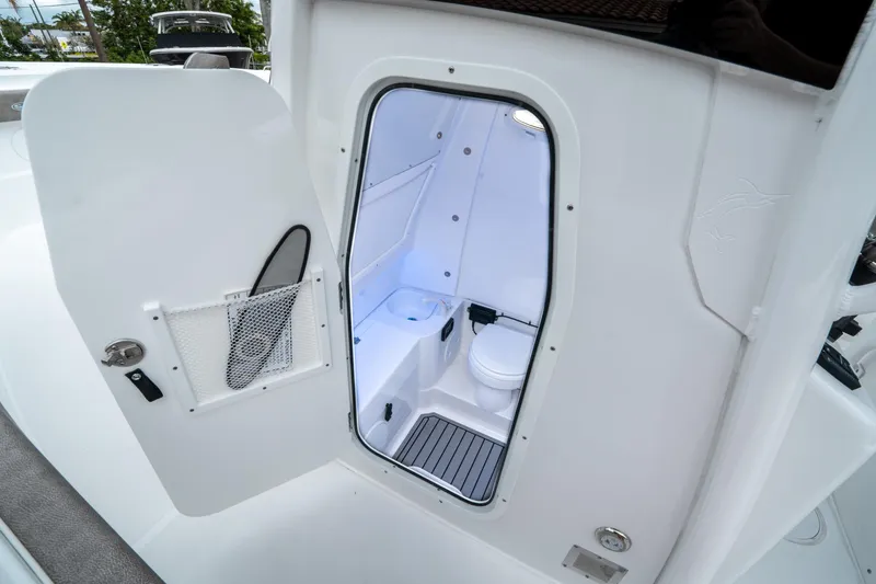 Slide: The Image of 2025 Sea Hunt Gamefish 28 CB boat interior with open door revealing compact bathroom. - 32