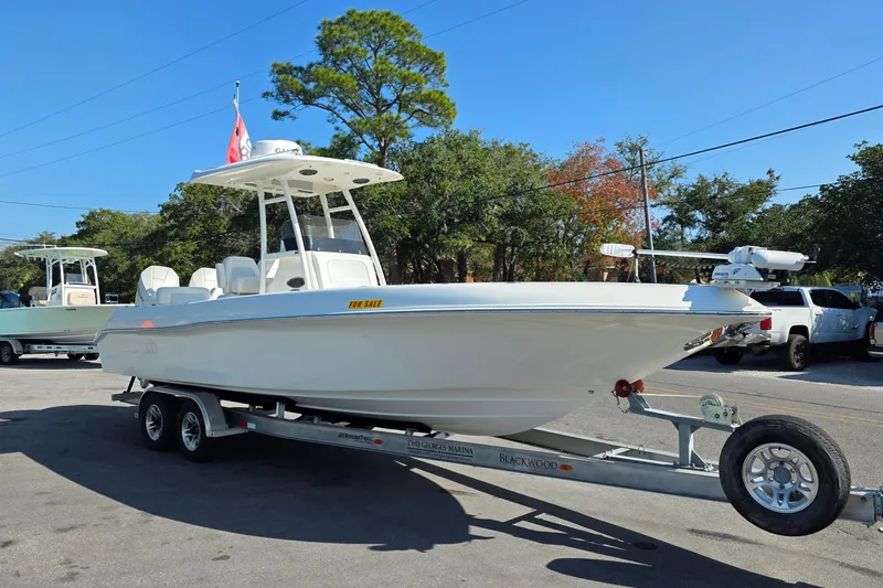 Slide: The Image of 2021 Blackwood 27 boat on trailer outside a blue building under clear sky. - 1