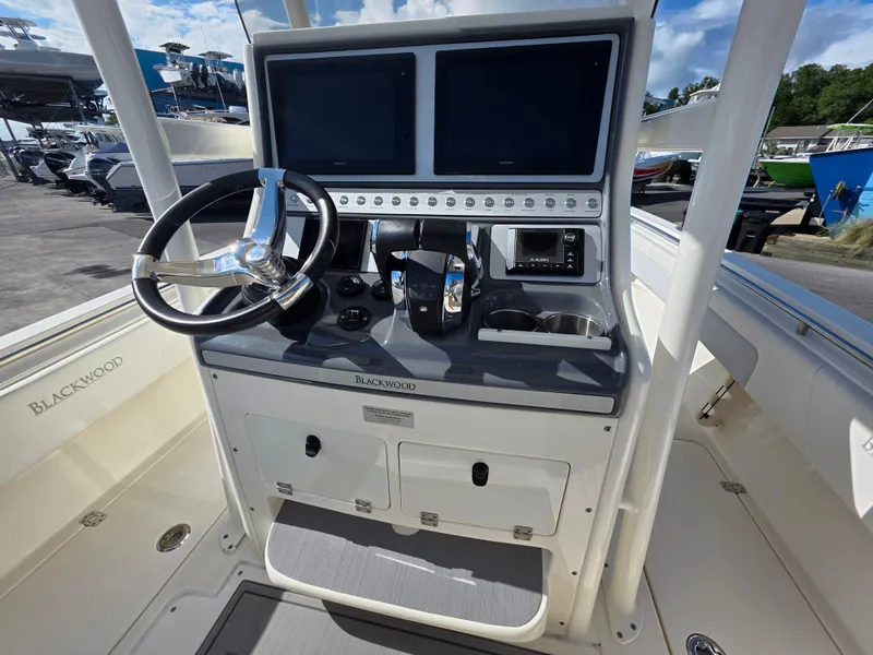 Slide: The Image of 2021 Blackwood 27 boat console with dual screens, steering wheel, and control panel. - 21