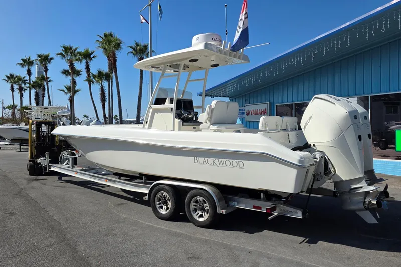 Slide: The Image of 2021 Blackwood 27 boat on trailer with Mercury outboard engine, parked outdoors. - 3
