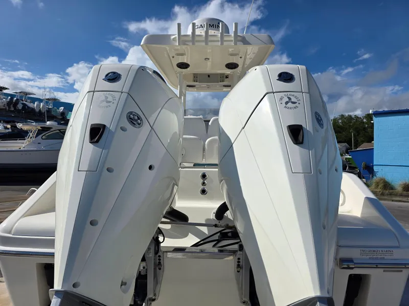 Slide: The Image of 2021 Blackwood 27 boat with dual outboard engines, docked under a clear blue sky. - 9