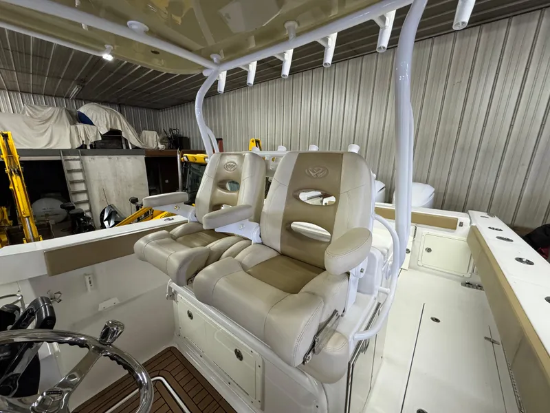 Slide: The Image of 2017 Southport 33 FE boat interior with beige captain seats in a storage facility. - 16