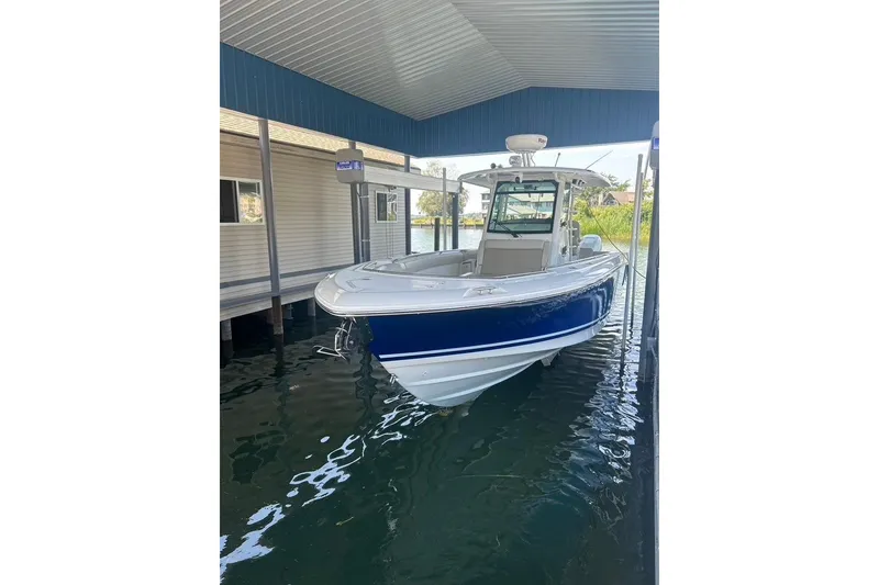 The Image of 2016 Boston Whaler 330 Outrage boat docked under a covered marina. - 0