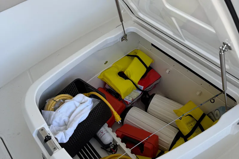 Slide: The Image of Storage compartment on 2016 Boston Whaler 330 Outrage with life jackets and boating gear. - 13