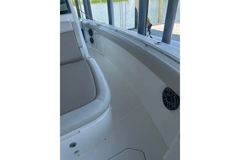 Slide: The Image of 2016 Boston Whaler 330 Outrage interior with seating and speaker, docked by water. - 31