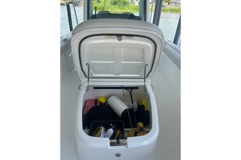Slide: The Image of Open storage compartment on 2016 Boston Whaler 330 Outrage boat, containing various boating gear. - 50