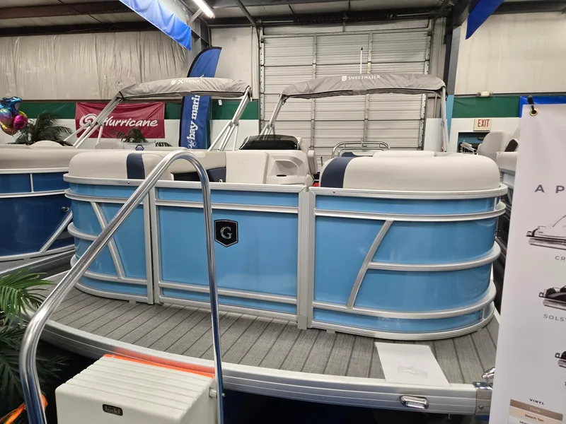 Slide: The Image of 2025 Godfrey Sweetwater 2086 C pontoon boat displayed indoors, featuring blue and white design. - 0