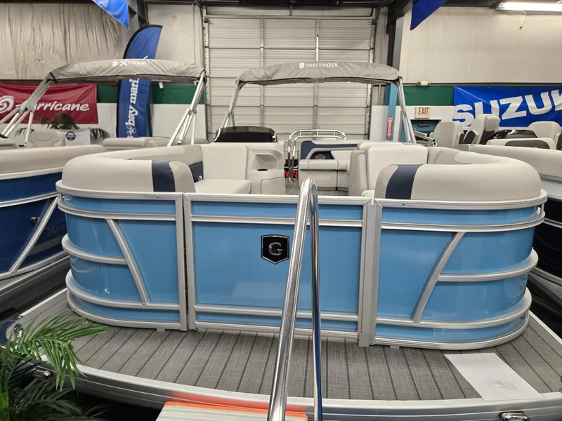 Slide: The Image of 2025 Godfrey Sweetwater 2086 C pontoon boat in showroom, featuring blue and white design. - 1
