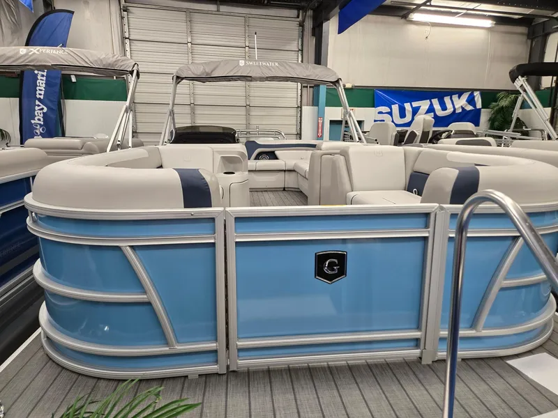Slide: The Image of 2025 Godfrey Sweetwater 2086 C pontoon boat in showroom, featuring blue and white design. - 2
