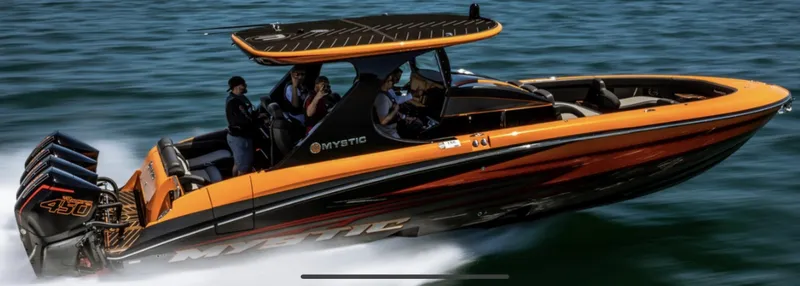The Image of 2023 Mystic Powerboats M3800 speeding on water, vibrant orange and black design. - 0