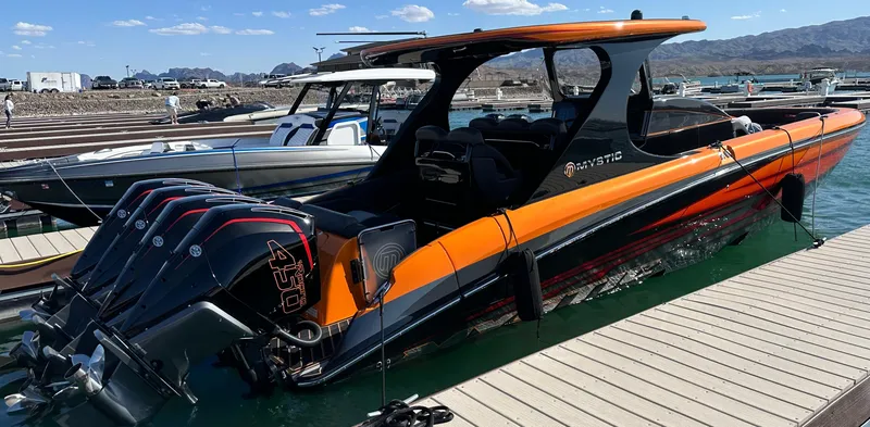 Slide: The Image of 2023 Mystic Powerboats M3800, sleek orange and black design, docked at marina. - 9