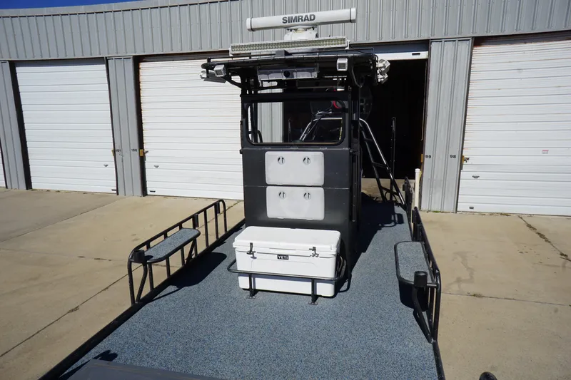 Slide: The Image of 2016 Boat Right 25'8'' Custom Flat boat with Simrad equipment, parked outside a garage. - 10