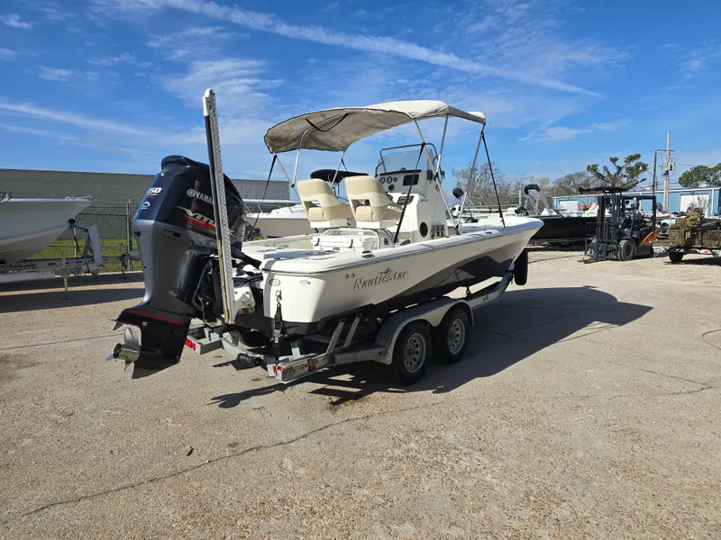 Slide: The Image of 2016 NauticStar 227 XTS boat on trailer, parked outside a warehouse. - 2