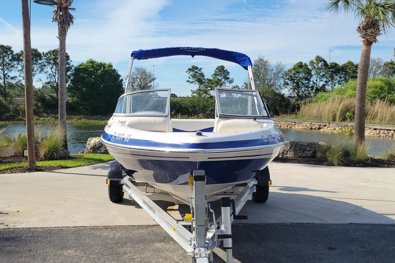 Slide: The Image of 2007 Tahoe Q4 L boat on trailer, parked near a scenic lake with trees. - 2