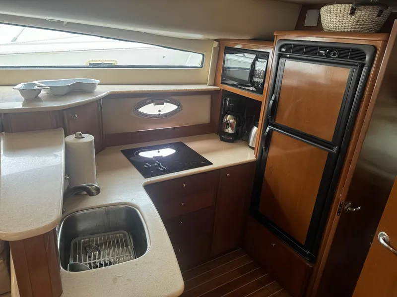 Slide: The Image of 2005 Meridian 459 Motoryacht kitchen with sink, stove, fridge, and wooden cabinetry. - 9