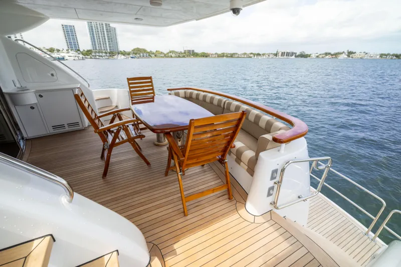 Slide: The Image of 2005 Hatteras 80 Motor Yacht deck with wooden chairs and table overlooking water. - 12