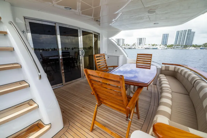 Slide: The Image of 2005 Hatteras 80 Motor Yacht deck with wooden furniture and waterfront view. - 13