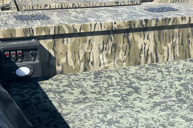 Slide: The Image of 2025 SeaArk 1652 MVJT boat with Tohatsu motor, camo design, parked on gravel. - 6