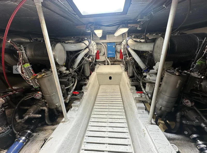 Slide: The Image of Engine room of a 1987 Ocean Yachts 48 Super Sport, showcasing dual engines and mechanical components. - 12