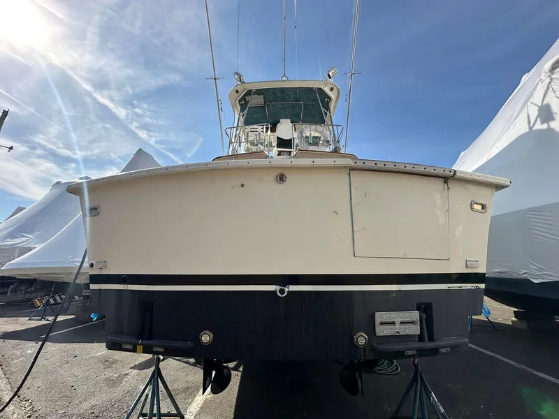 Slide: The Image of 1987 Ocean Yachts 48 Super Sport boat on stands, viewed from the rear under a clear sky. - 15