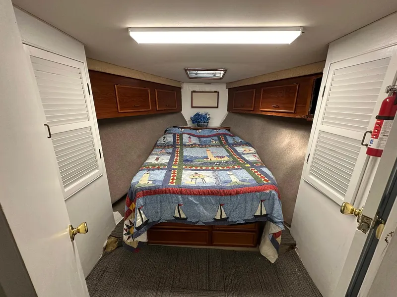 Slide: The Image of 1987 Ocean Yachts 48 Super Sport cabin with nautical-themed bedding and wooden storage cabinets. - 9