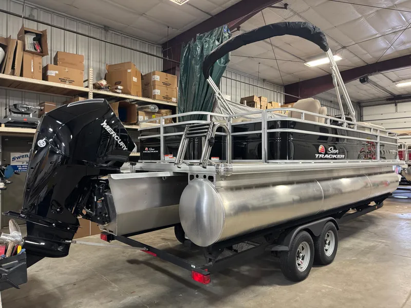 Slide: The Image of 2025 Sun Tracker Sportfish 24 XP3 pontoon boat in a warehouse setting. - 2