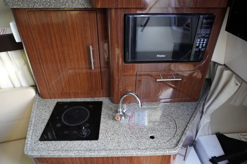 Slide: The Image of Compact kitchen area in a 2013 Regal 28 Express boat with microwave and stovetop. - 10