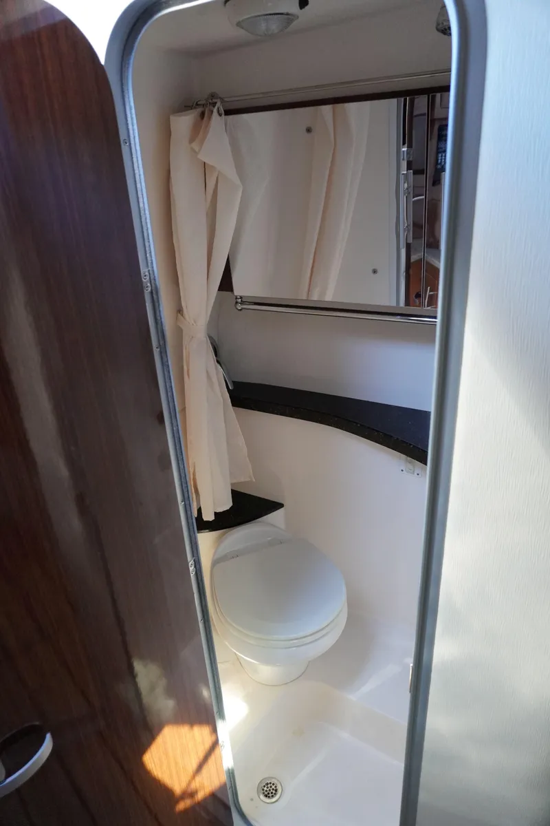 Slide: The Image of 2013 Regal 28 Express boat bathroom interior with toilet and mirror. - 14