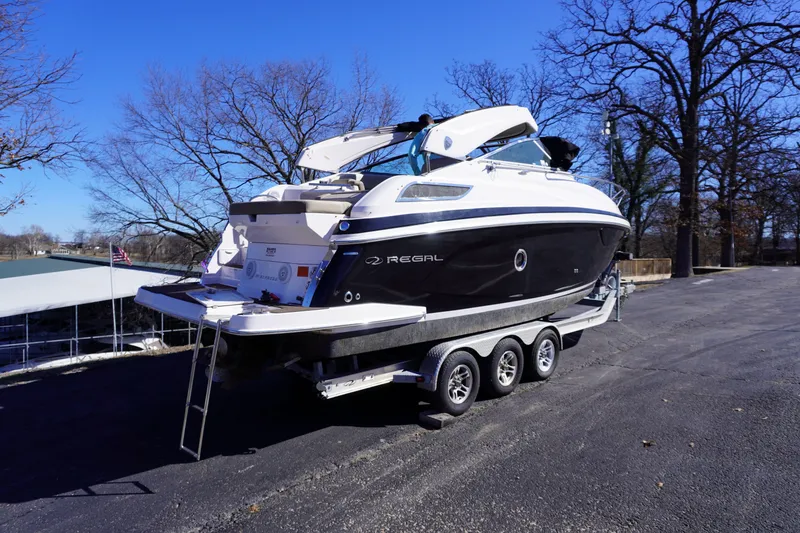 Slide: The Image of 2013 Regal 28 Express boat on trailer, parked outdoors, clear blue sky. - 2