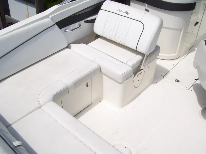 Slide: The Image of 2015 Sea Ray 240 Sundeck interior with white cushioned seating and storage compartment. - 10