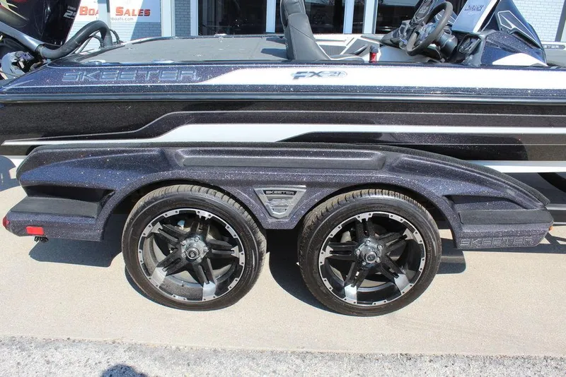 Slide: The Image of 2018 Skeeter FX21 LE boat trailer with dual black wheels and sleek design. - 17