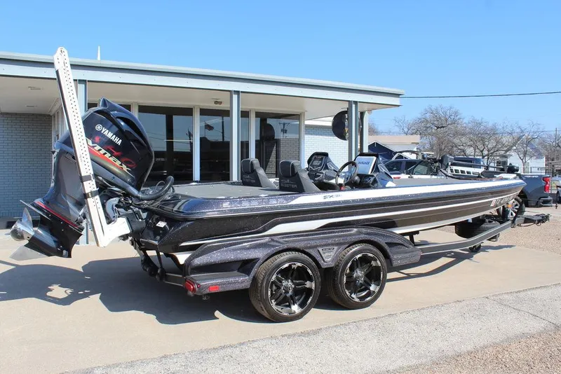 Slide: The Image of 2018 Skeeter FX21 LE bass boat with Yamaha engine, parked on a trailer outside a building. - 3
