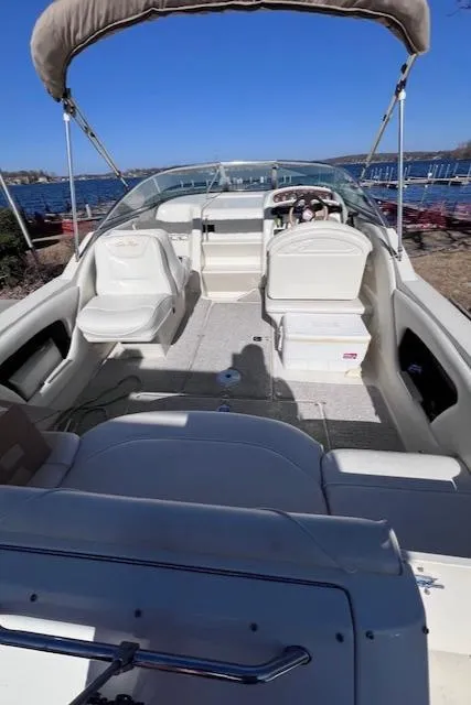 Slide: The Image of 2000 Sea Ray 245 Weekender boat with open deck and seating, docked by a lake. - 13