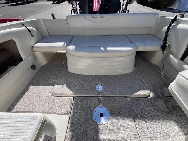 Slide: The Image of 2000 Sea Ray 245 Weekender boat interior with cushioned seating and carpeted flooring. - 2