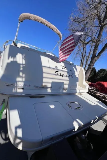 Slide: The Image of 2000 Sea Ray 245 Weekender boat with American flag, docked under clear blue sky. - 7