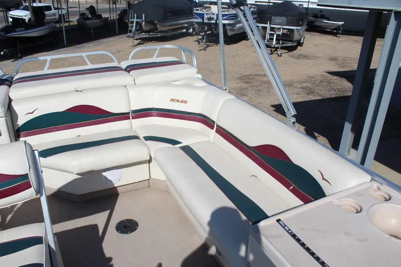 Slide: The Image of 1997 Monark Pontoon boat interior with white and multicolored seating in a storage area. - 10