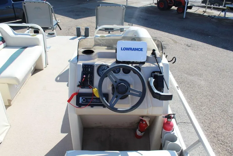 Slide: The Image of 1997 Monark Pontoon boat dashboard with steering wheel and Lowrance navigation system. - 16