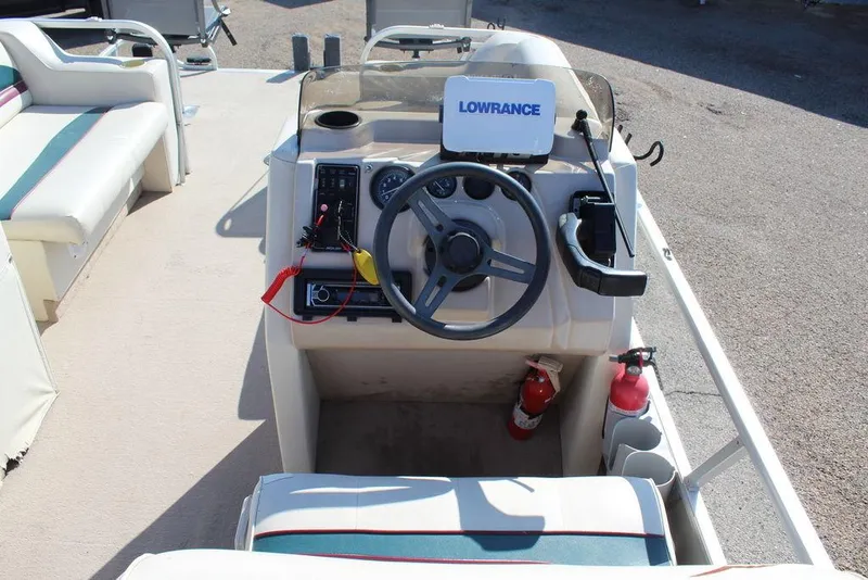 Slide: The Image of 1997 Monark Pontoon boat dashboard with steering wheel and Lowrance navigation system. - 19